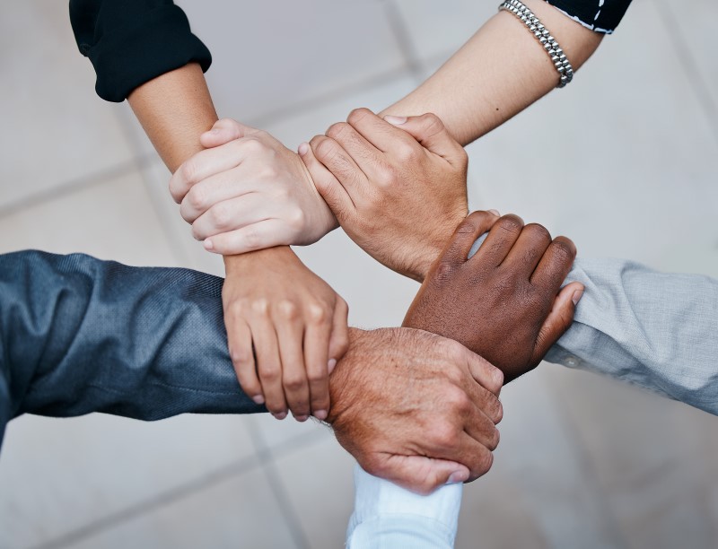 Business people, office and holding hands in circle for support, collaboration and professional synergy. Teamwork, solidarity and group in huddle for productivity, diversity and project management